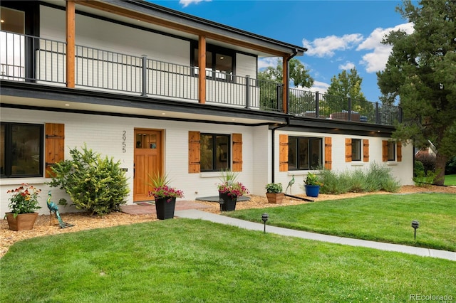 back of house featuring a balcony and a yard