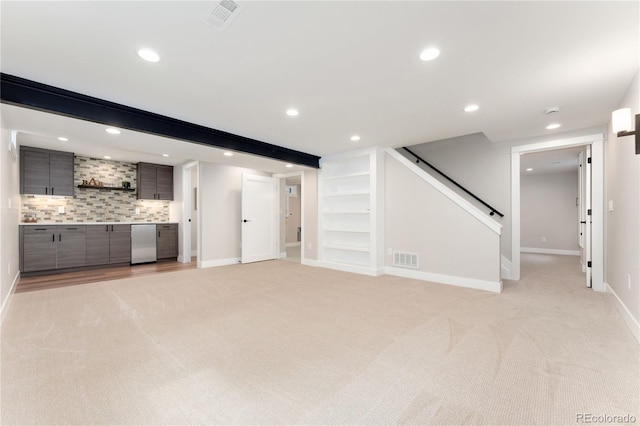 unfurnished living room featuring beam ceiling and light colored carpet