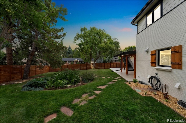 yard at dusk featuring a patio