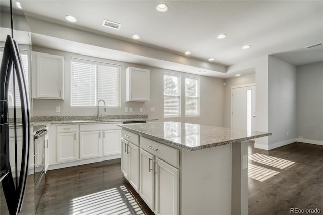 16069 E Elk Dr, Denver, CO 80239 - kitchen featuring dark wood-style floors, fridge, a center island, white cabinets, and recessed lighting