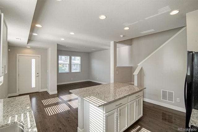 16069 E Elk Dr, Denver, CO 80239 - kitchen with dark wood finished floors, white cabinetry, recessed lighting, light stone counters, and freestanding refrigerator
