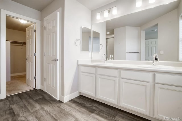 16069 E Elk Dr, Denver, CO 80239 - full bathroom featuring wood finished floors, double vanity, a stall shower, and a walk in closet
