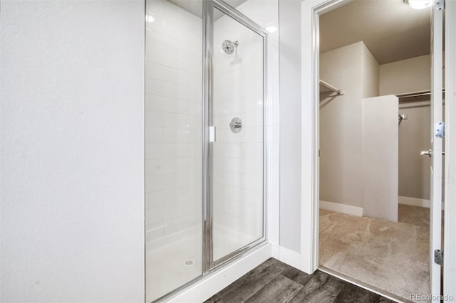 16069 E Elk Dr, Denver, CO 80239 - full bathroom featuring a walk in closet, a shower stall, and wood finished floors