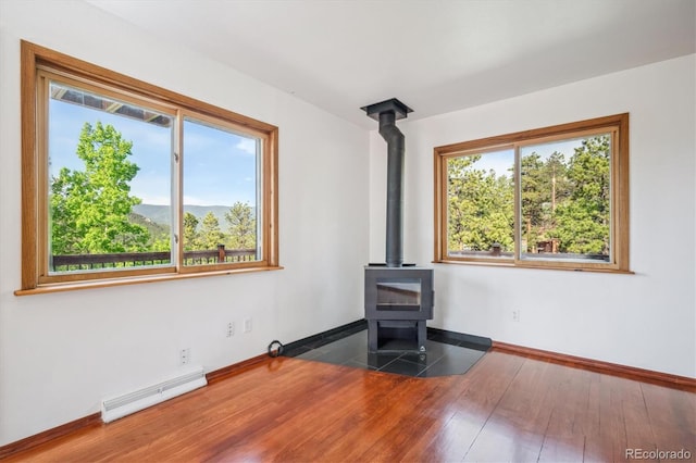 429 Overlook Dr, Bailey, CO 80421 - unfurnished living room featuring a wood stove, baseboard heating, and wood finished floors