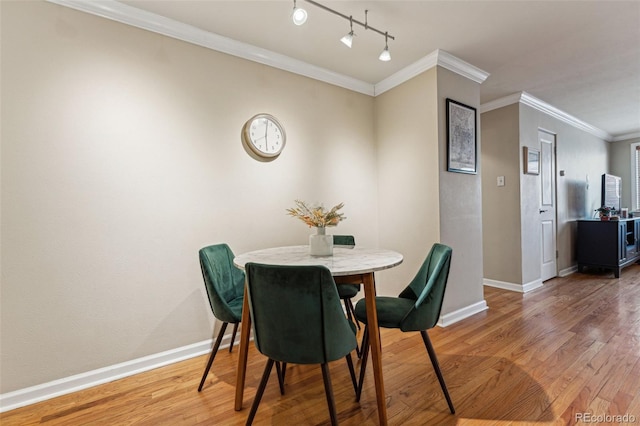 dining room with crown molding, light wood-style flooring, and baseboards