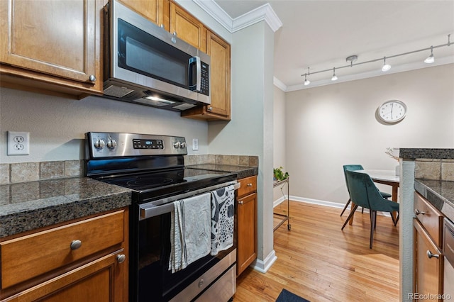 kitchen with light wood-style floors, appliances with stainless steel finishes, tile counters, brown cabinetry, and crown molding