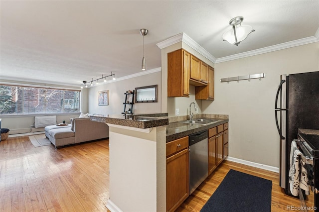 kitchen featuring a sink, open floor plan, ornamental molding, appliances with stainless steel finishes, and tile counters