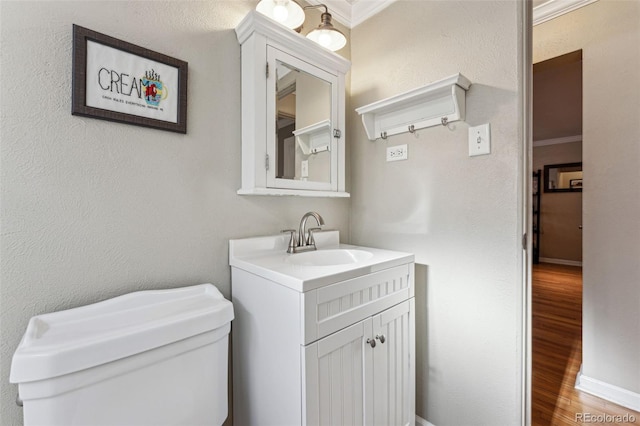 bathroom with ornamental molding, a textured wall, vanity, and wood finished floors