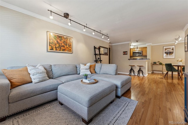 living room featuring ornamental molding, light wood-type flooring, and baseboards