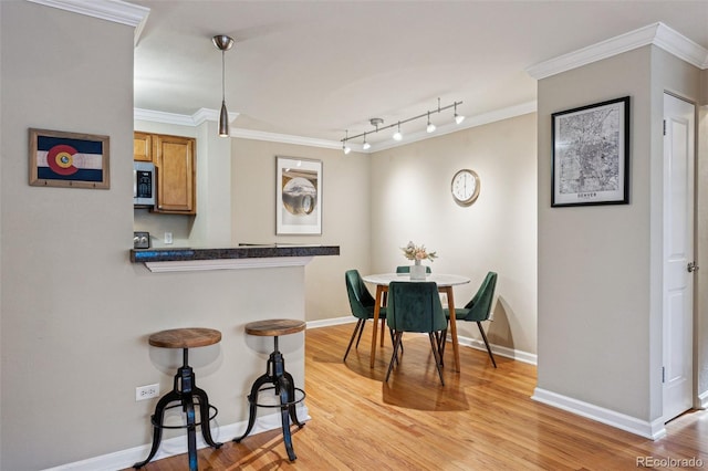 dining room featuring light wood-type flooring, baseboards, and crown molding