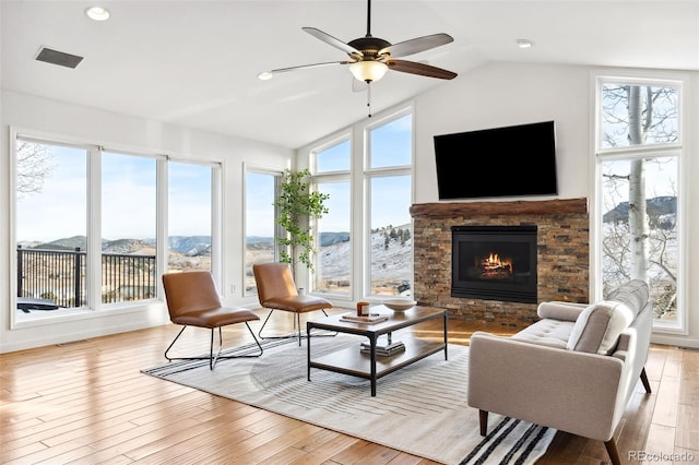 sunroom / solarium featuring lofted ceiling, a stone fireplace, and ceiling fan