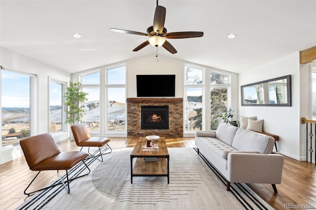 living room featuring vaulted ceiling, a healthy amount of sunlight, a fireplace, and light hardwood / wood-style floors