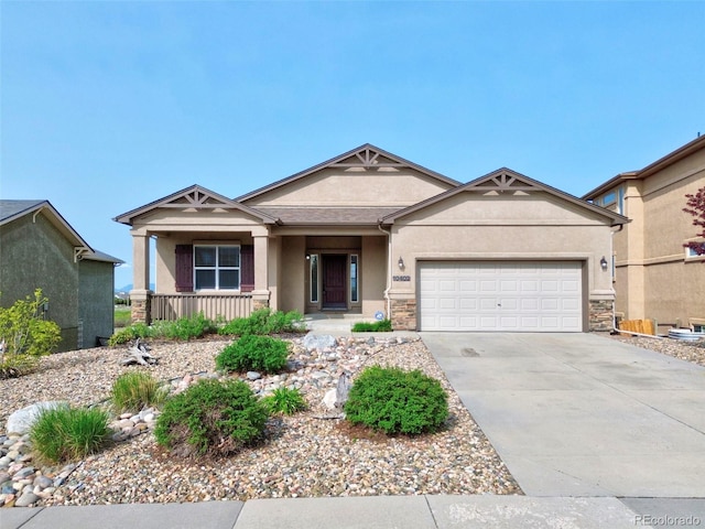 10402 Capital Peak Way, Peyton, CO 80831 - view of front of property with stucco siding, a porch, an attached garage, driveway, and stone siding