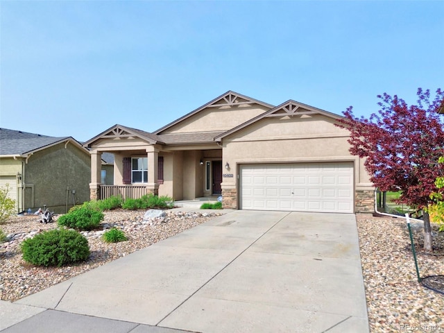 10402 Capital Peak Way, Peyton, CO 80831 - view of front facade with stucco siding, a garage, covered porch, concrete driveway, and stone siding