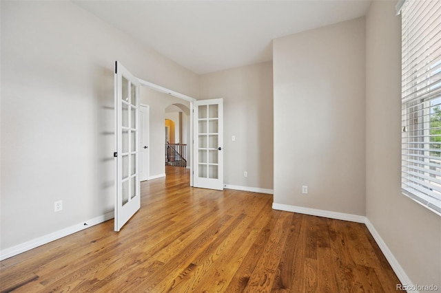 10402 Capital Peak Way, Peyton, CO 80831 - spare room featuring french doors, arched walkways, light wood-style floors, and baseboards