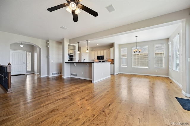 10402 Capital Peak Way, Peyton, CO 80831 - unfurnished living room featuring a ceiling fan, arched walkways, light wood finished floors, and baseboards