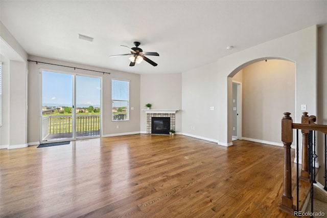 10402 Capital Peak Way, Peyton, CO 80831 - unfurnished living room with a ceiling fan, wood finished floors, arched walkways, a fireplace with flush hearth, and baseboards