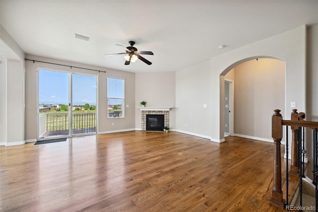 10402 Capital Peak Way, Peyton, CO 80831 - unfurnished living room featuring a ceiling fan, wood finished floors, arched walkways, a fireplace, and baseboards