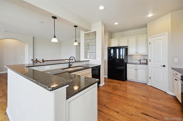 10402 Capital Peak Way, Peyton, CO 80831 - kitchen with black appliances, a sink, arched walkways, light wood-style flooring, and dark stone counters