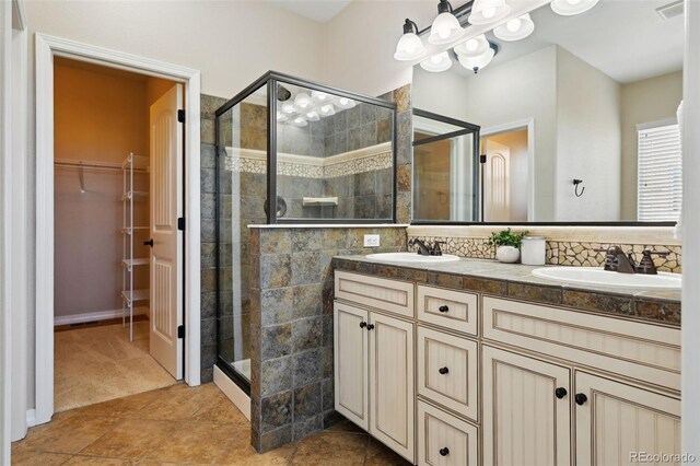 10402 Capital Peak Way, Peyton, CO 80831 - bathroom featuring a shower stall, double vanity, a walk in closet, tasteful backsplash, and tile patterned flooring