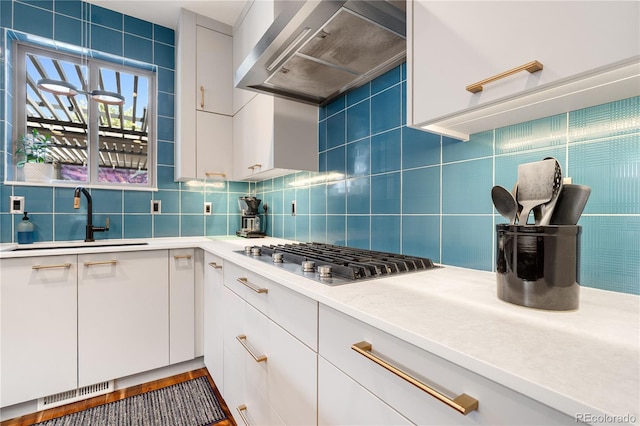 2334 Lowell Blvd, Denver, CO 80211 - kitchen with wall chimney exhaust hood, stainless steel gas cooktop, tasteful backsplash, white cabinets, and light countertops