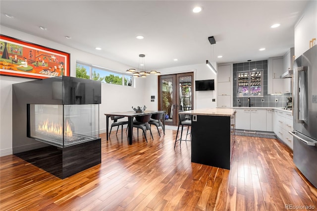 2334 Lowell Blvd, Denver, CO 80211 - kitchen featuring high end refrigerator, light wood-style flooring, decorative backsplash, a kitchen island, and wall chimney exhaust hood