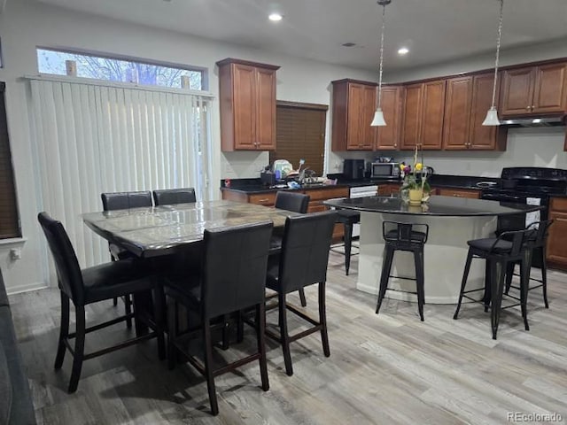 4995 S Algonquian Way, Aurora, CO 80016 - kitchen featuring stainless steel microwave, under cabinet range hood, dark countertops, a breakfast bar, and recessed lighting