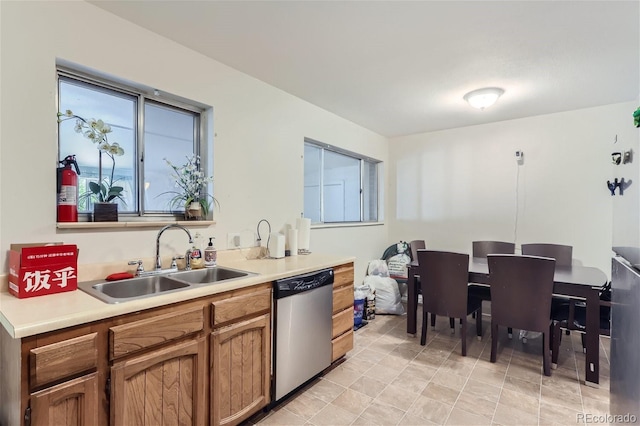 kitchen with dishwasher, light countertops, a sink, and brown cabinets