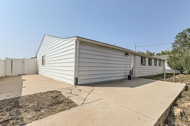 view of outbuilding with driveway, fence, and a gate