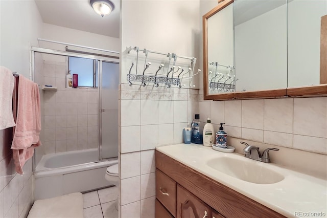 bathroom featuring toilet, enclosed tub / shower combo, tile walls, and vanity