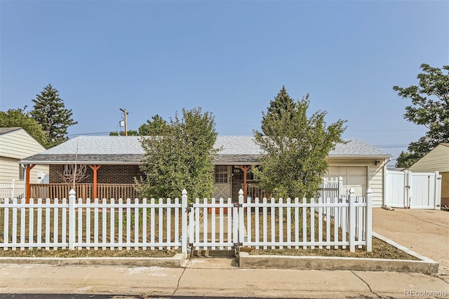 ranch-style home with driveway, a shingled roof, a fenced front yard, an attached garage, and a gate