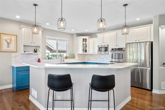 kitchen featuring blue cabinetry, white cabinetry, appliances with stainless steel finishes, and tasteful backsplash