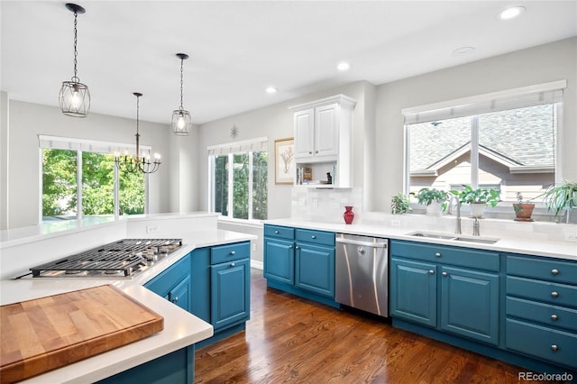 kitchen featuring sink, appliances with stainless steel finishes, white cabinets, blue cabinets, and decorative light fixtures