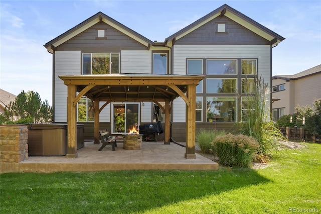 back of house featuring a patio, a fire pit, a yard, a hot tub, and a gazebo