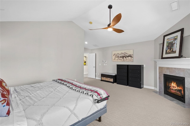 carpeted bedroom featuring lofted ceiling, a tile fireplace, and ceiling fan