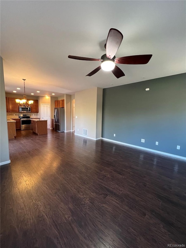 unfurnished living room with ceiling fan with notable chandelier and dark hardwood / wood-style floors