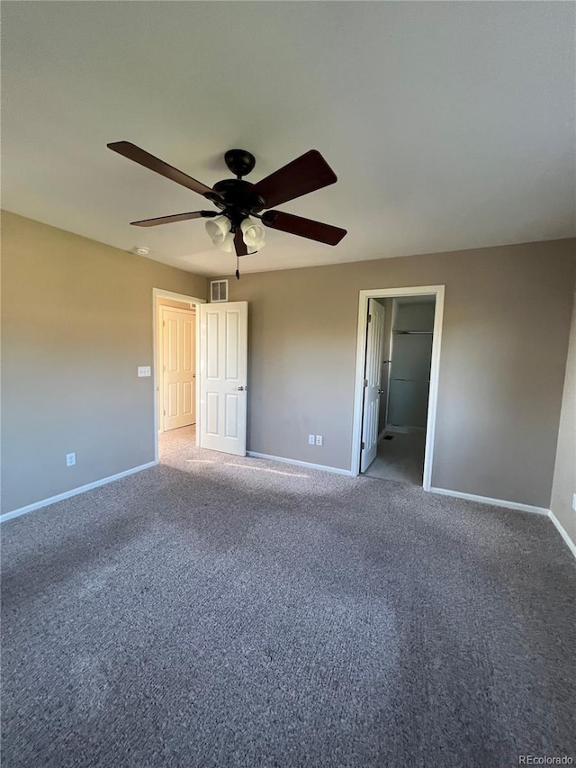 unfurnished bedroom featuring carpet flooring, a spacious closet, and ceiling fan