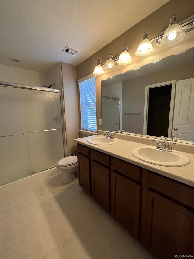 bathroom featuring a textured ceiling, walk in shower, vanity, and toilet