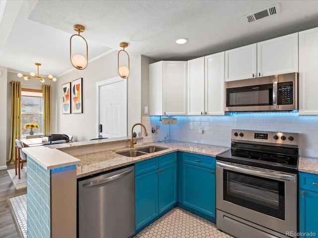 kitchen with sink, stainless steel appliances, white cabinets, blue cabinets, and decorative light fixtures