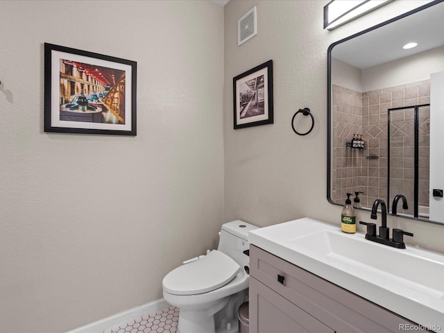 bathroom featuring vanity, a tile shower, tile patterned floors, and toilet