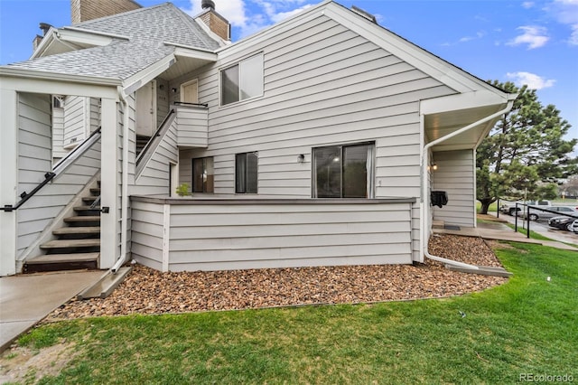 17004 E Tennessee Dr Unit 103, Aurora, CO 80017 - rear view of property featuring a chimney, a yard, and a shingled roof