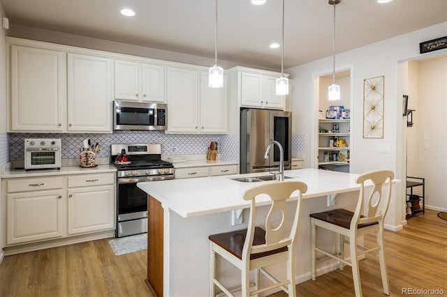 kitchen with white cabinetry, appliances with stainless steel finishes, a center island with sink, and sink