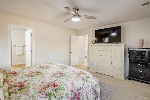 bedroom featuring ceiling fan, ensuite bathroom, and light colored carpet