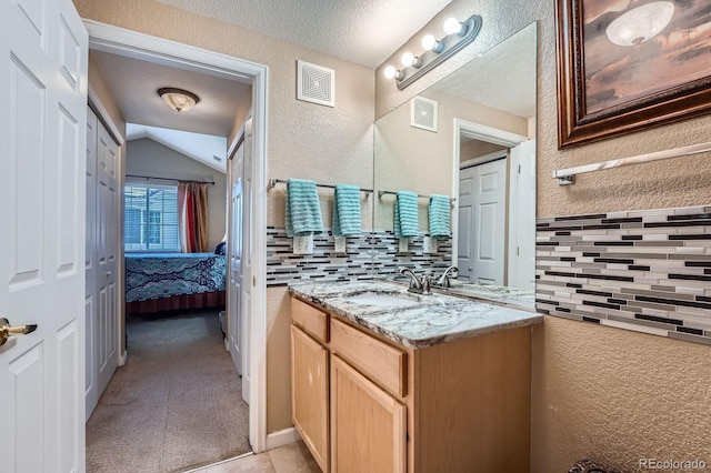 22560 E Ontario Dr Unit 204, Aurora, CO 80016 - bathroom with vanity, lofted ceiling, ensuite bathroom, decorative backsplash, and a textured ceiling