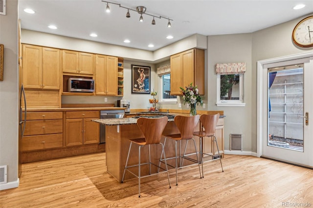 kitchen with a breakfast bar, a peninsula, stainless steel appliances, and light wood-style floors