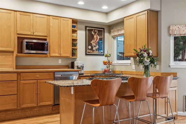 kitchen with a kitchen bar, recessed lighting, stone countertops, stainless steel appliances, and open shelves