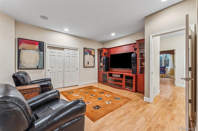 living room featuring recessed lighting, baseboards, and light wood-type flooring