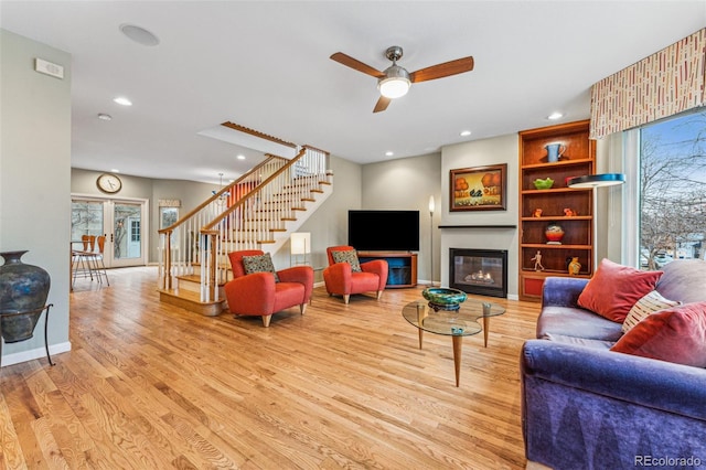 living room featuring stairway, recessed lighting, a glass covered fireplace, and wood finished floors