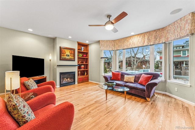 living room with a glass covered fireplace, wood finished floors, and baseboards