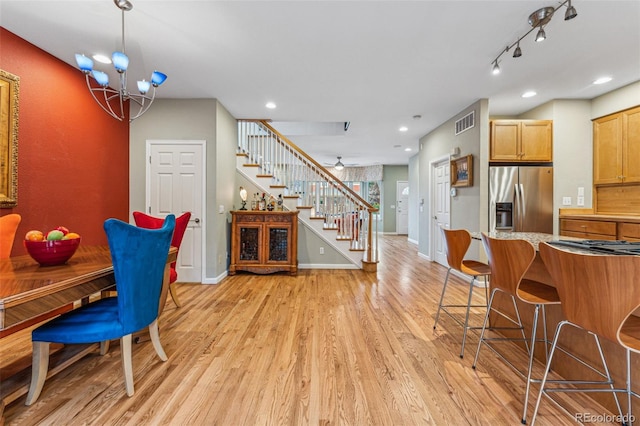 dining space featuring baseboards, visible vents, stairs, light wood-type flooring, and a chandelier